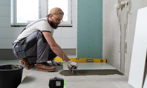 Pose de carrelage pour rénovation de salle de bain Carreleur posant du carrelage au sol dans le cadre d’une rénovation de salle de bain