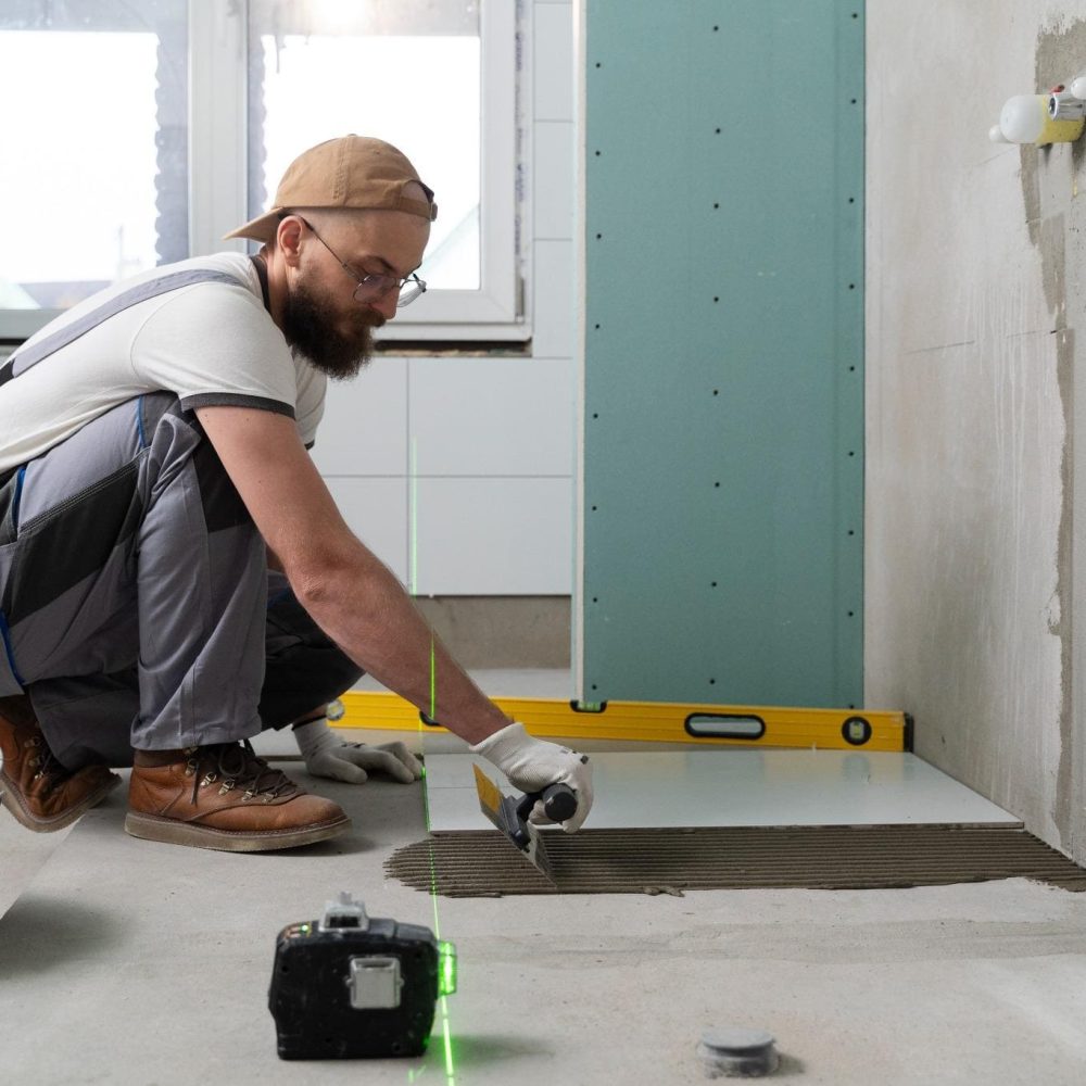 Pose de carrelage pour rénovation de salle de bain Carreleur posant du carrelage au sol dans le cadre d’une rénovation de salle de bain